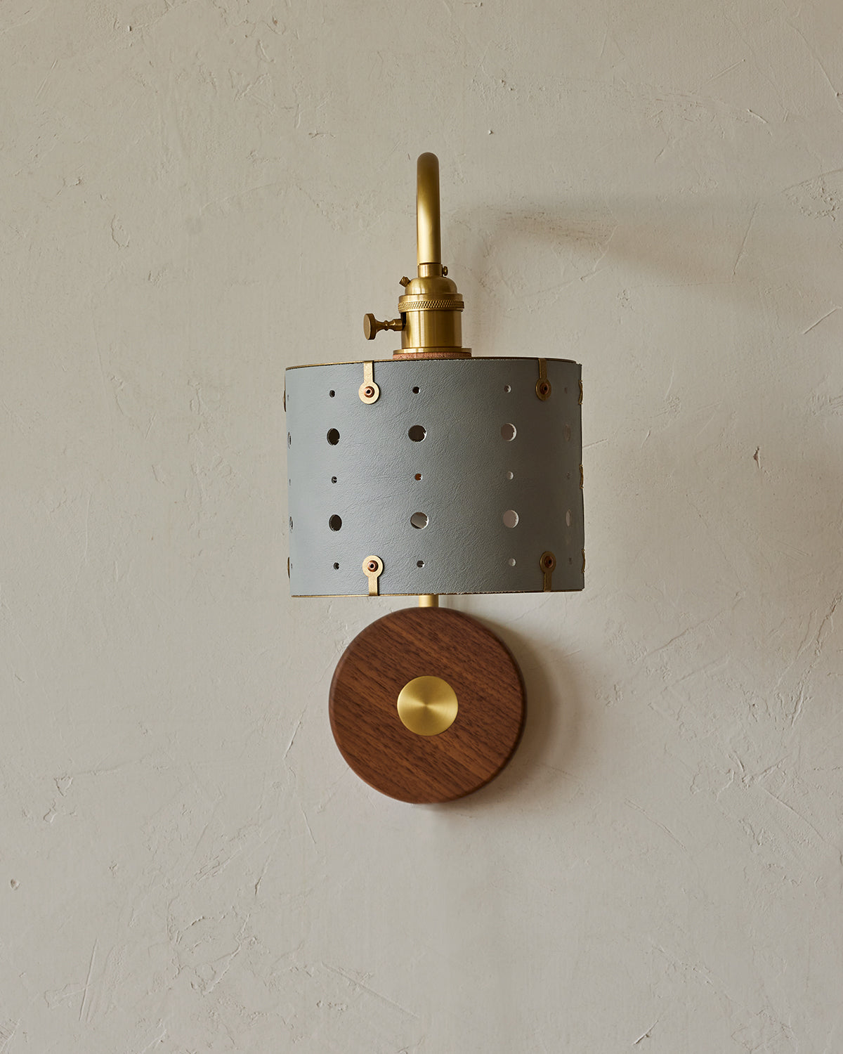 Articulating satin brass sconce with blue handstitched leather shade and walnut backplate #leather-finish_cloud blue #wiring_hardwired