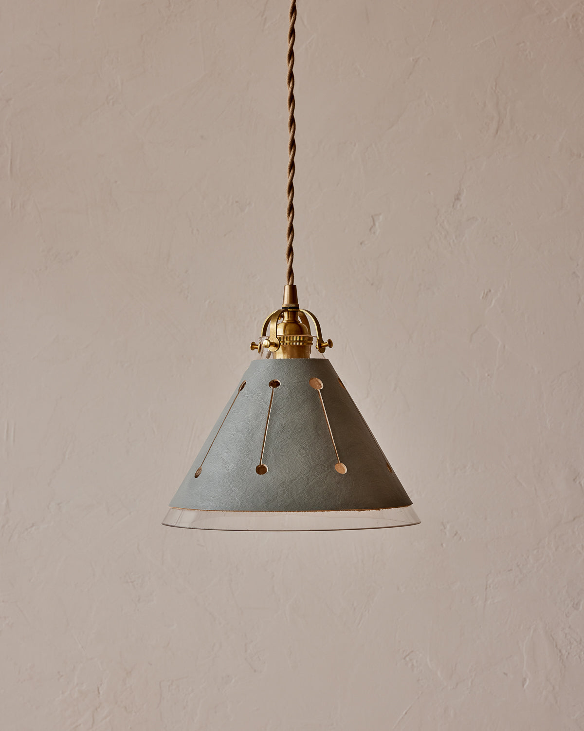 A pendant light with a blue leather sleeve and a conical glass shade, featuring brass fitter and twisted cloth cord. #leather-finish_cloud blue