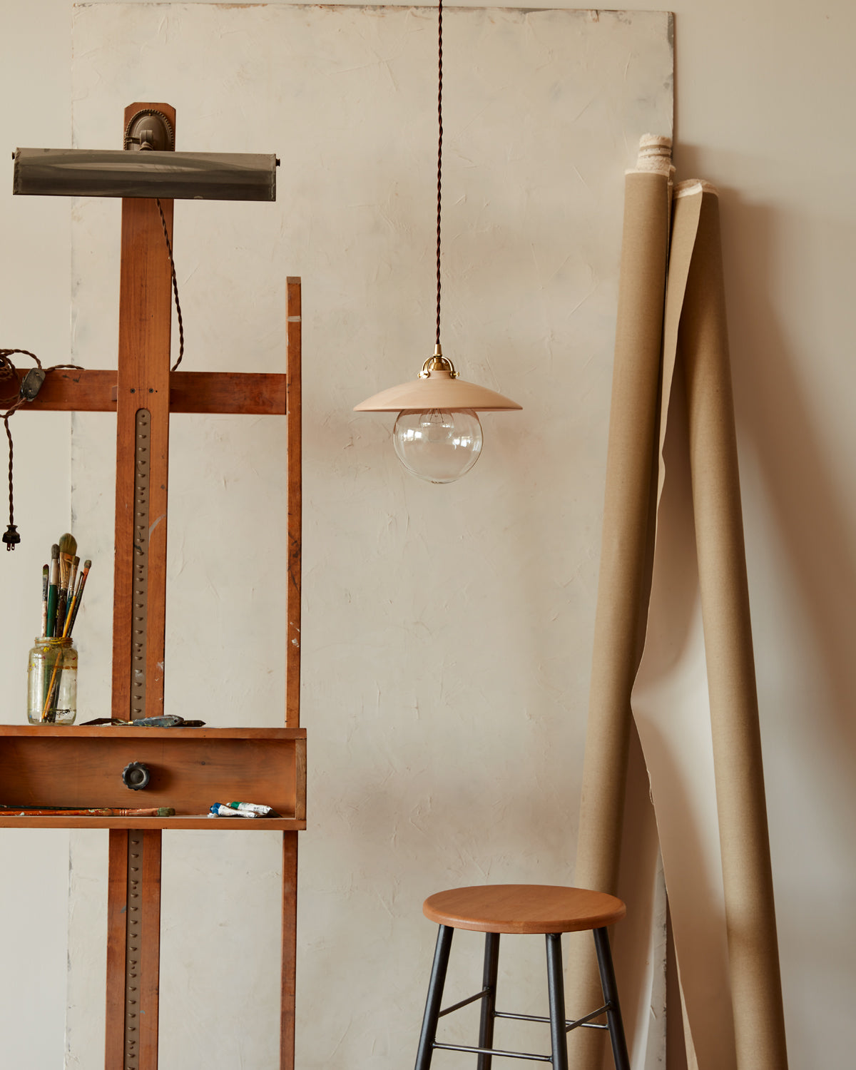 Pendant light with large clear glass globe and decorative wooden clear maple shade hanging in art studio. Made by Lostine in Philadelphia. Simple interior design, made in the USA. Warm American Modern Design #shade-finish_clear maple #Cord-Color---Glass_Brown Cord - Clear Globe