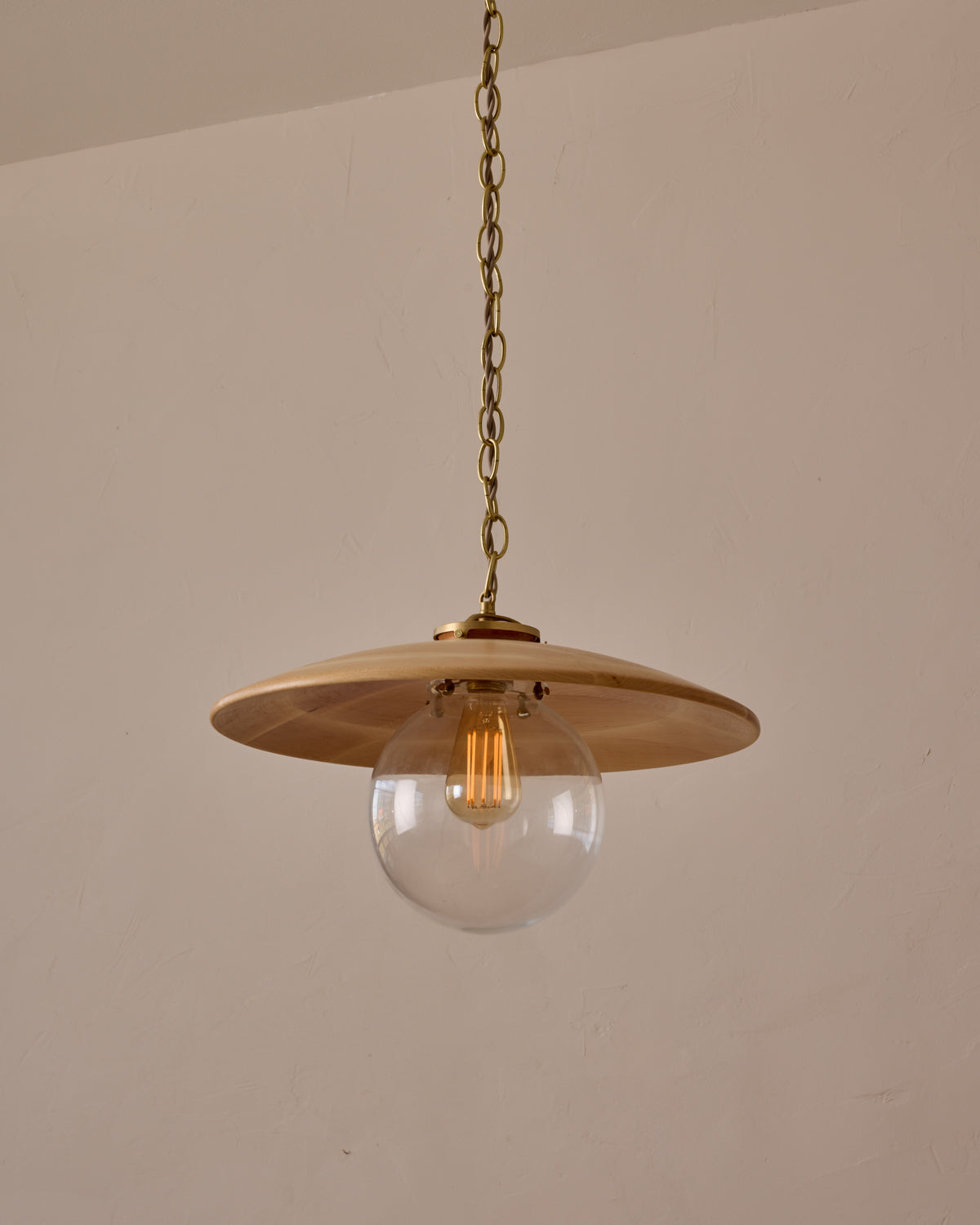 Large pendant light with oversized clear glass globe and decorative wooden clear maple shade with brass chain  #shade-finish_natural maple #globe_clear glass #cord-color_beige