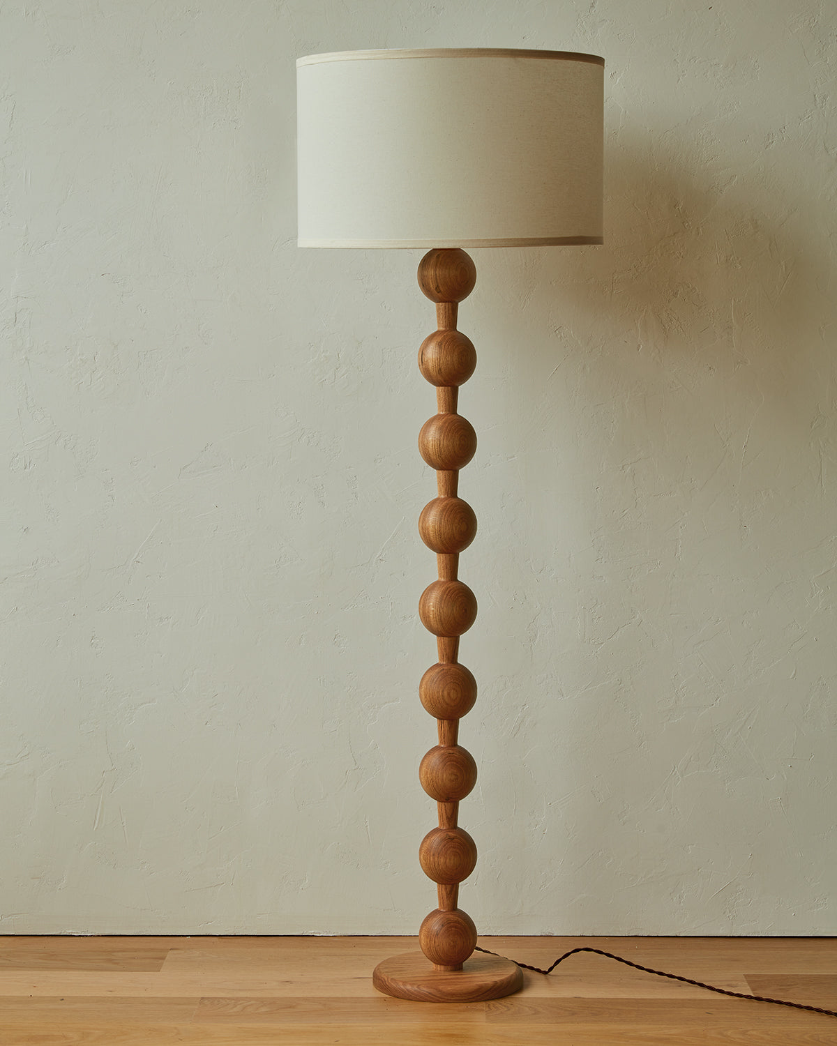 Tall sculptural solid red oak floor lamp with barbell design in natural finish with ivory linen drum shade, best seller, made in the USA 
#color_natural red oak
#shade-color_ivory linen