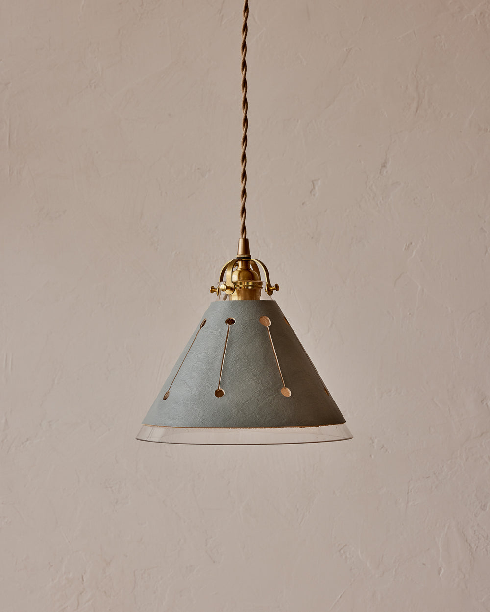 A pendant light with a blue leather sleeve and a conical glass shade, featuring brass fitter and twisted cloth cord.   #leather-finish_cloud blue